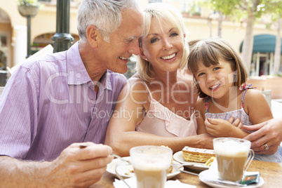 Grandparents With Granddaughter Enjoying Coffee And Cake In Caf?
