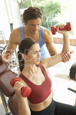 Young Woman Working With Weights In Gym With Personal Trainer