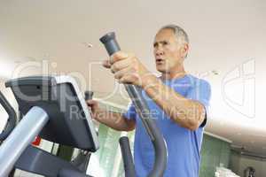 Senior Man On Cross Trainer In Gym