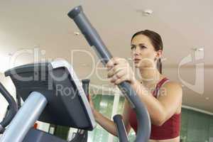 Woman On Cross Trainer Machine In Gym