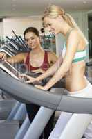 Woman Working With Female Personal Trainer On Running Machine In