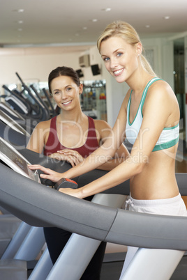 Woman Working With Female Personal Trainer On Running Machine In