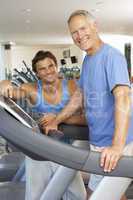 Man Working With Personal Trainer On Running Machine In Gym