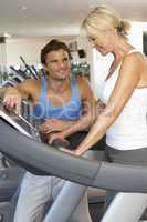 Senior Woman Working With Personal Trainer On Running Machine In