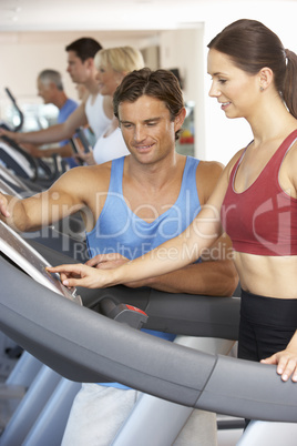 Woman Working With Personal Trainer On Running Machine In Gym