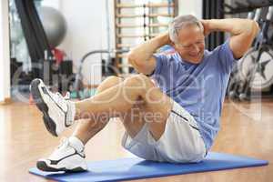 Senior Man Doing Sit Ups In Gym