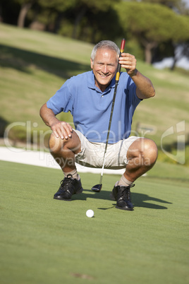 Senior Male Golfer On Golf Course Lining Up Putt On Green