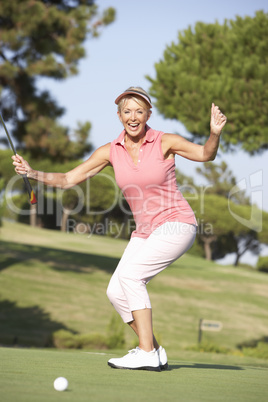 Senior Female Golfer On Golf Course Lining Up Putt On Green