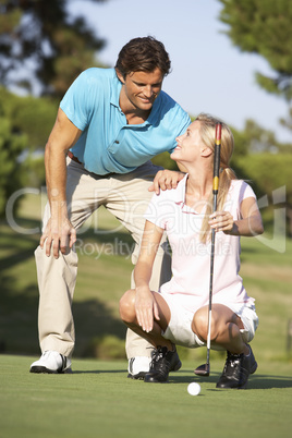 Couple Golfing On Golf Course Lining Up Putt On Green