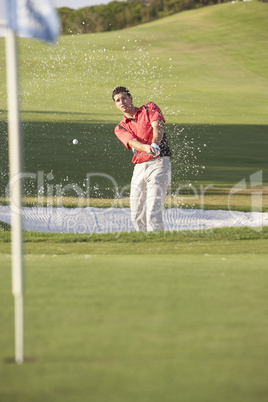 Male Golfer Playing Bunker Shot On Golf Course