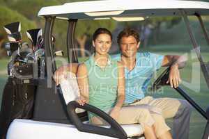 Couple Riding In Golf Buggy On Golf Course