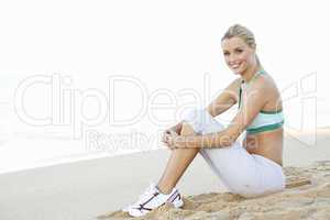 Young Woman In Fitness Clothing Resting After Exercise On Beach