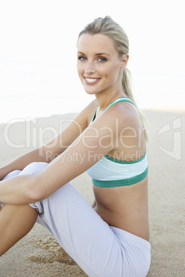 Young Woman In Fitness Clothing Resting After Exercise On Beach