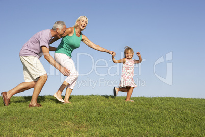 Senior couple, with granddaughter,  running though field