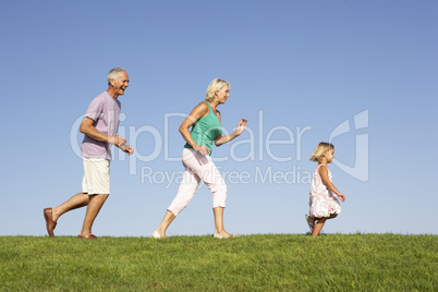 Senior couple, with granddaughter,  running though field