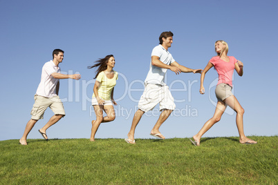 Young couples running through field