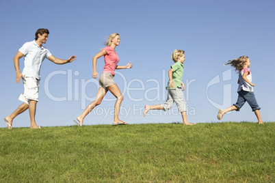 Young family, parents with children,  running through field