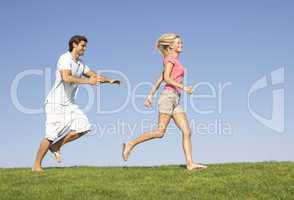 Young couple running through field