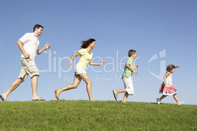 Young family, parents with children,  running through field