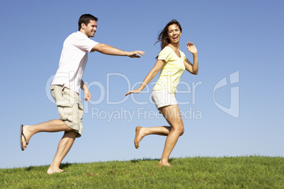 Young couple running through field