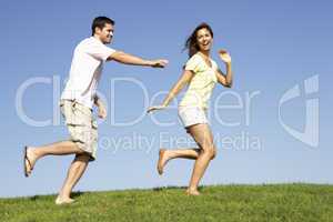 Young couple running through field