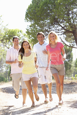 Two young couples, together, running in park