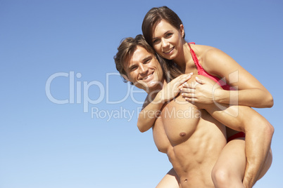 Young Couple Enjoying Piggyback On Beach Holiday