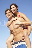 Young Couple Enjoying Piggyback On Beach Holiday