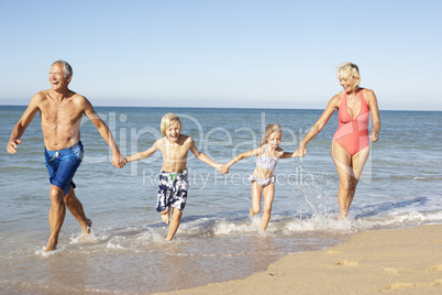 Grandparents With Grandchildren Enjoying Beach Holiday Together