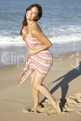 Young Woman Relaxing On Beach Wearing Wrap