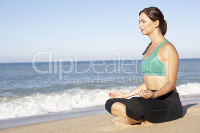 Young Woman In Fitness Clothing Meditating On Beach