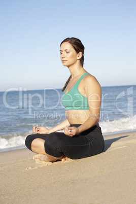 Young Woman In Fitness Clothing Meditating On Beach