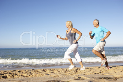 Senior Couple In Fitness Clothing Running Along Beach