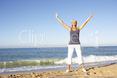 Senior Woman In Fitness Clothing Stretching On Beach