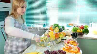 Pregnant woman mixing fruit salad