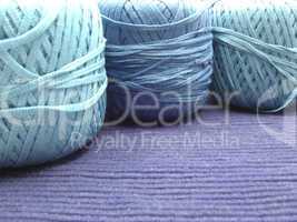 Drei  blaue Wollknaeuel arrangiert auf blauer Decke