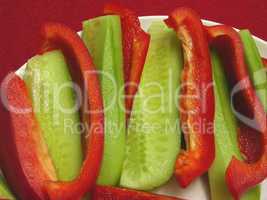 Rote Paprika und Gurkenstreifen auf weissem Teller und rotem Tis