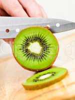 Woman's hands cutting kiwi