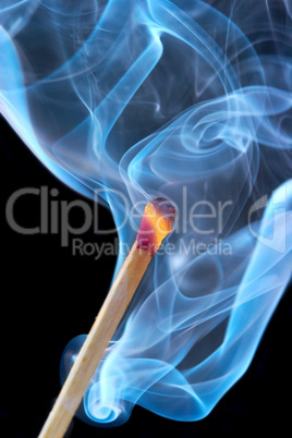 Photo of a burning match in a smoke on a black background