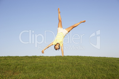 Young woman cartwheels in field