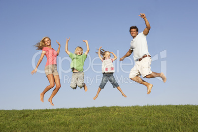 Young couple with children jump in a field
