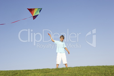 Young boy poses with kite in a field