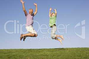 Senior man with grandson jumping in air