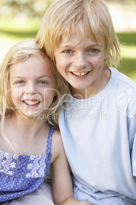 Brother and sister pose in a park