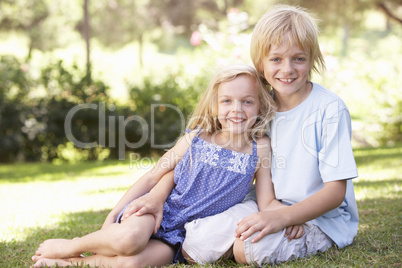 Brother and sister pose in a park