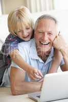 Senior man with young boy using laptop computer