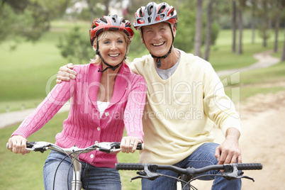 Senior couple riding bicycle in park