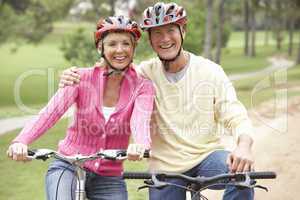 Senior couple riding bicycle in park