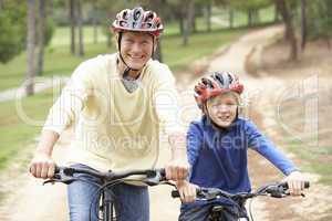 Grandfather and grandson riding bicycle in park