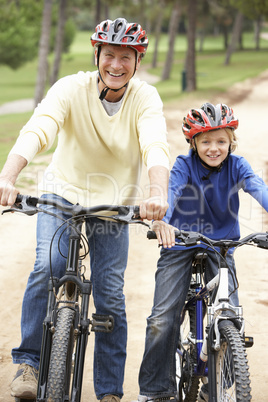 Grandfather and grandson riding bicycle in park